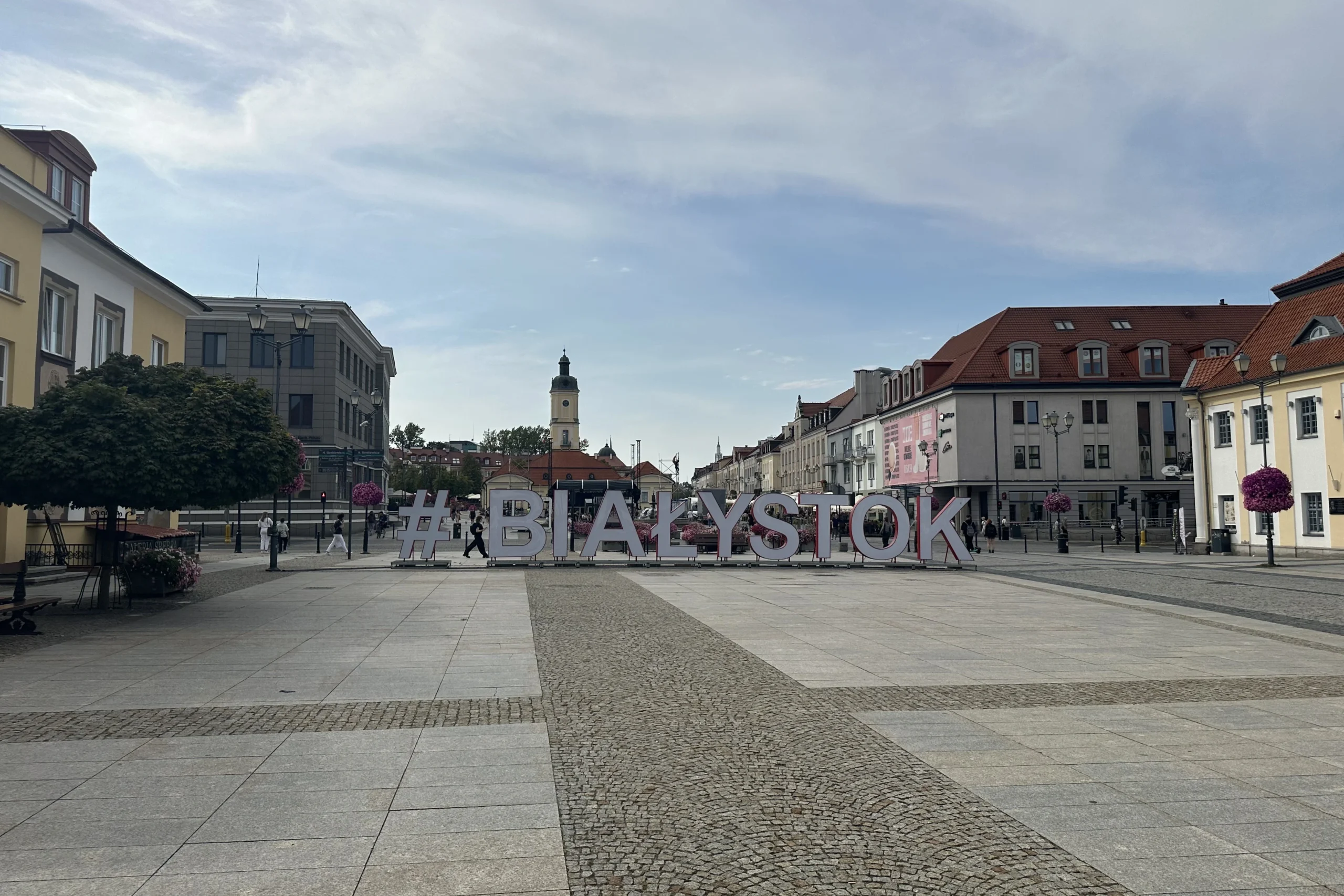 Duży napis Białystok ustawiony na Rynku Kościuszki, z dawnym ratuszem i zabudową centrum w tle.